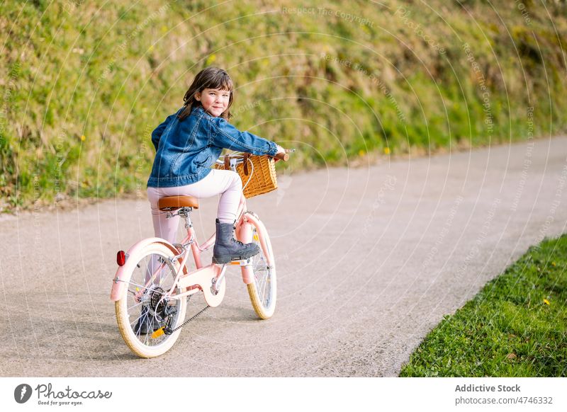 Cute girl sitting on bicycle kid park hobby leisure pastime childhood recreation ride basket activity summer bike transport smile summertime cute adorable