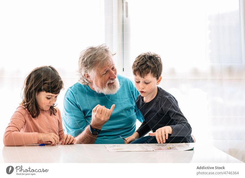 Grandfather teaching grandchildren to write grandfather study homework knowledge education primary cognition learn smart diligent boy girl sibling desk focus