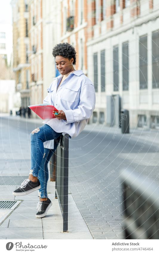 Smiling black woman reading documents on street student city urban feminine information knowledge smile positive female african american cheerful lady content