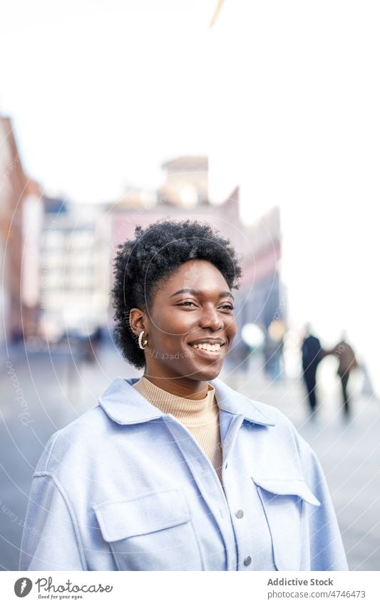 Smiling black woman in city street appearance style feminine enjoy urban smile building african american female summer glad happy casual positive content