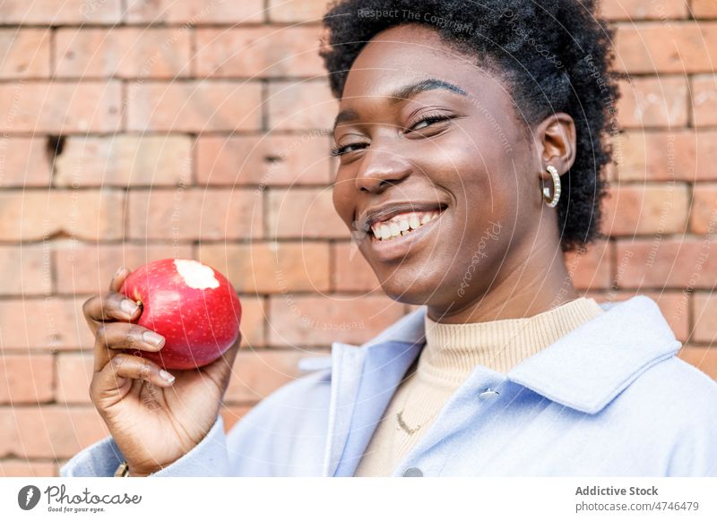 Black woman eating apple on street fruit healthy food happy city vitamin smile walkway style appearance feminine urban black delight cheerful african american