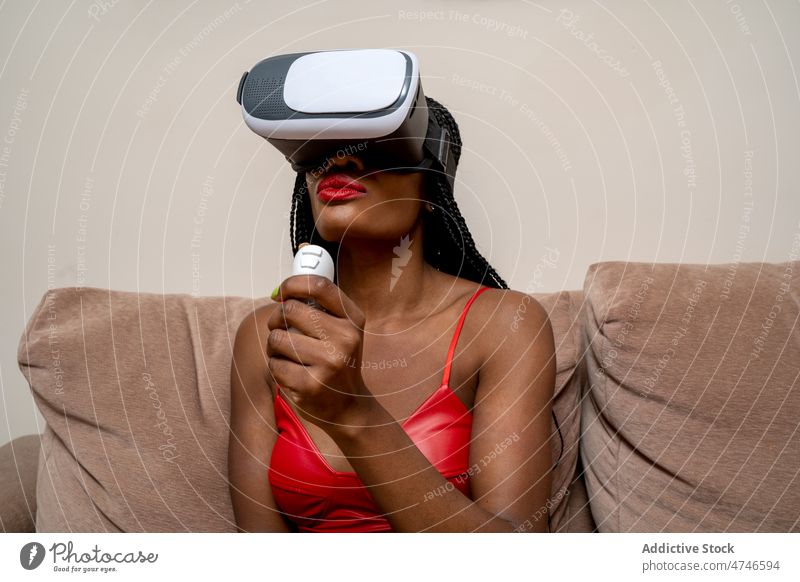 Black woman in VR goggles vr headset controller cyberspace futuristic explore simulate immerse living room experience virtual reality african american black