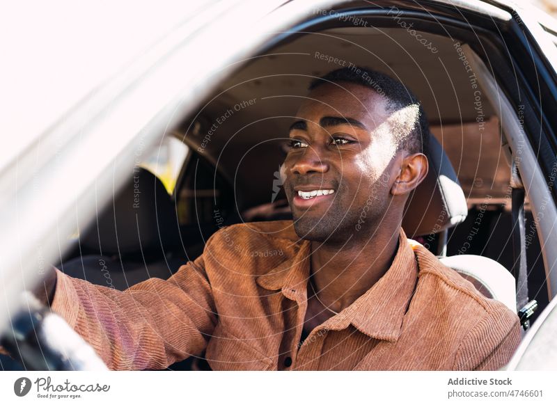 Cheerful black man in car driver automobile smile commute appearance window street steering wheel positive african american transport modern city trendy glad
