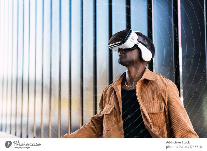 Black man exploring virtual reality in VR headset vr goggles city explore cyberspace futuristic building simulator modern african american black male experience