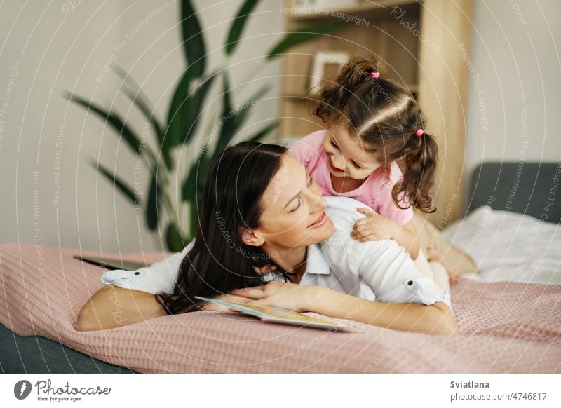 Portrait of a smiling mother and her baby in the bedroom. family love mom home daughter lying child happy cute little care motherhood portrait pretty female