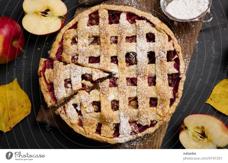 baked round traditional apple pie on brown wooden board and fresh red apples, top view food fruit dessert homemade pastry cake delicious sweet crust cinnamon