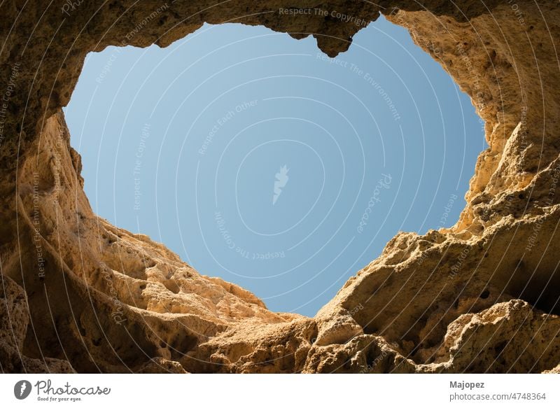 Stone cave with a heart shaped hole on the roof. Blue sky seen from inside the cave. Algarve, Portugal nature hiking park arch sandstone geology natural