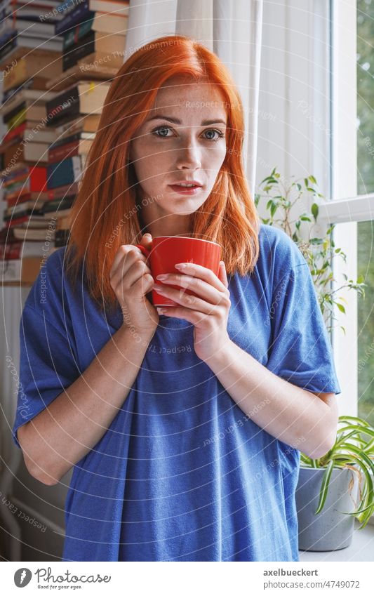 young woman standing with coffee cup at window in her apartment Young woman at home Coffee Coffee cup real people Window Flat (apartment) Cup To have a coffee