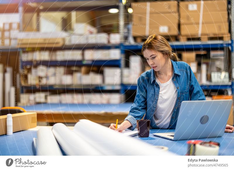 Woman using laptop at warehouse business cargo confident delivering delivery distribution employee factory female goods industrial industry job logistics