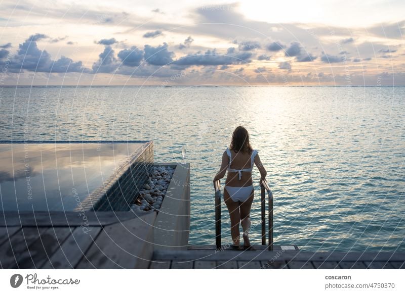 Woman on a villa overwater in Maldive Islands asian beach bikini blue body bungalow caribbean female girl holiday holidays hotel island ladder leisure lifestyle