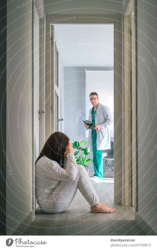 Physician looking at female patient with mental disorder sitting on floor in mental health center physician woman pajama hallway psychiatrist doctor medical