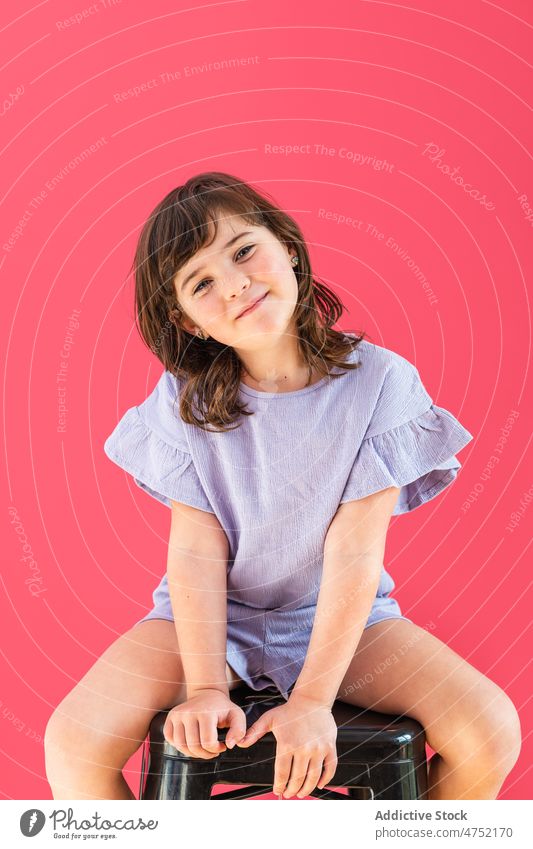 Cute girl sitting on stool in bright studio child carefree positive appearance model individuality personality smile overall cute childhood optimist adorable