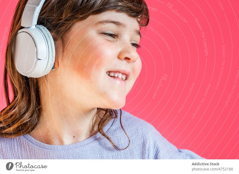 Joyful girl listening to music in headphones in studio laugh fun bright joy entertain happy playful enjoy child gadget pleasure expressive studio shot delight