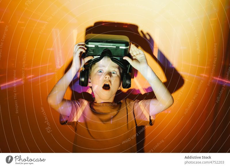 Amazed boy taking off VR helmet gamer shock vr headset take off neon illuminate videogame explore virtual reality bright amazed kid entertain device goggles