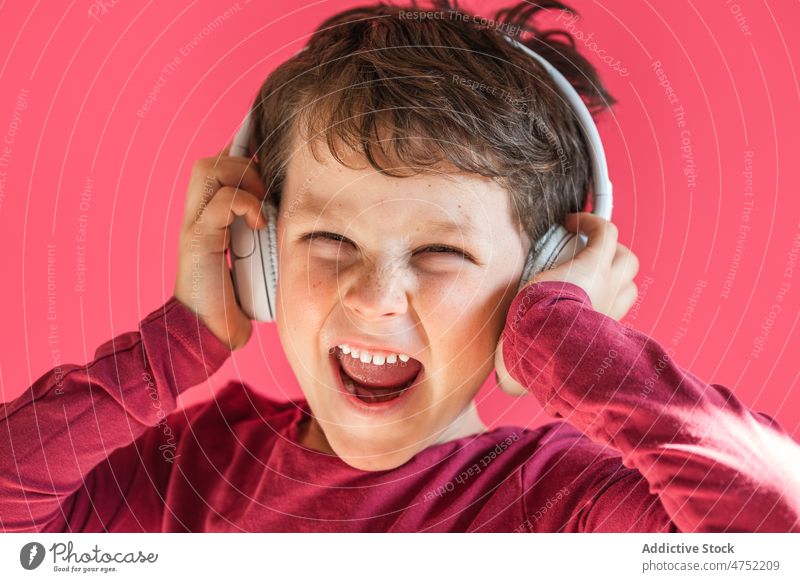 Boy listening to songs in wireless headphones in studio boy smile using playlist music leisure gadget child kid cheerful excited vivid carefree connection