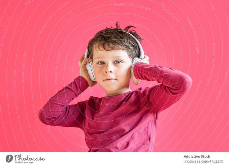 Boy listening to songs in wireless headphones in studio boy using playlist music leisure gadget smile child kid vivid carefree connection individuality