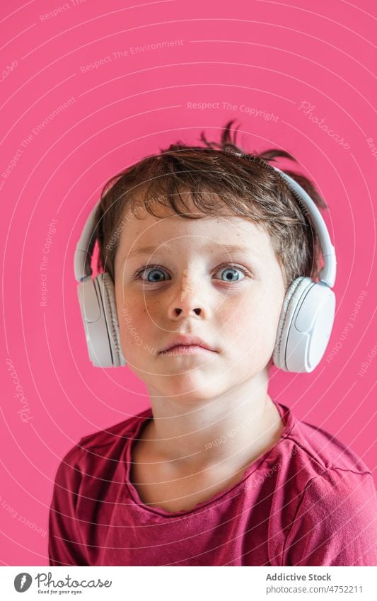 Boy listening to songs in wireless headphones in studio boy amazed using playlist music leisure gadget smile child kid vivid surprised carefree connection