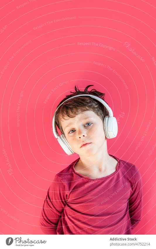 Boy listening to songs in wireless headphones in studio boy using playlist music leisure gadget smile child kid vivid carefree connection thoughtful