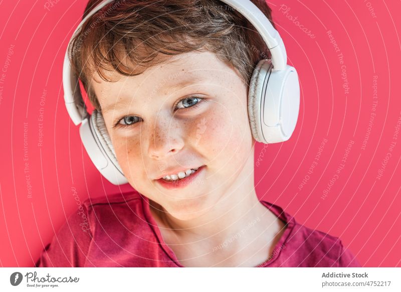 Boy listening to songs in wireless headphones in studio boy smile using playlist music leisure gadget child kid cheerful vivid carefree connection individuality