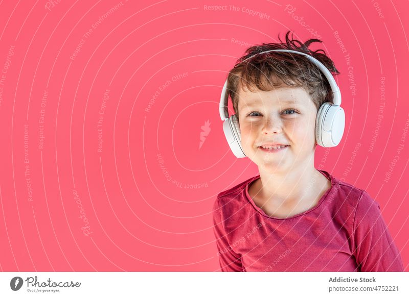 Boy listening to songs in wireless headphones in studio boy smile using playlist music leisure gadget child kid cheerful vivid carefree connection individuality