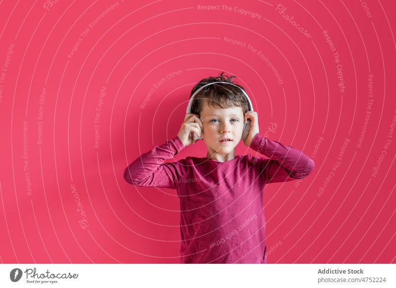 Boy listening to songs in wireless headphones in studio boy using playlist music leisure gadget smile child kid vivid carefree connection individuality