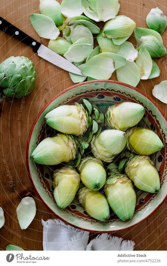 Bowl with peeled artichokes on wooden table fresh unpeeled ripe bowl healthy food vegetarian cook knife kitchen culinary prepare raw ingredient recipe harvest