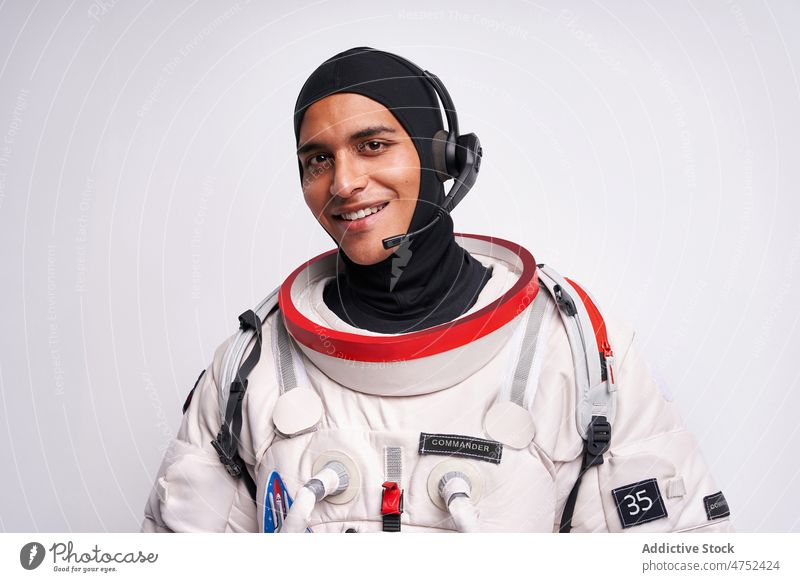 Smiling ethnic astronaut in spacesuit with headset for cosmos flight man ready earth portrait smile hispanic studio discovery prepare male spaceman latin happy