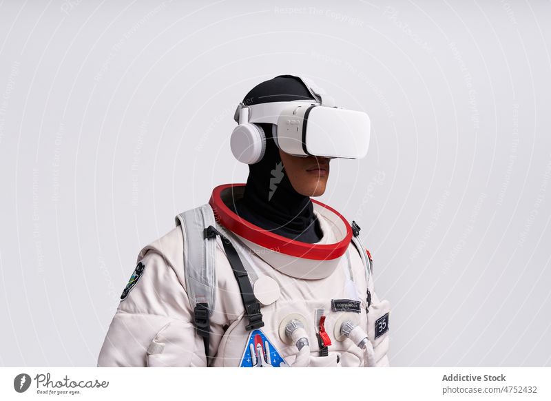 Ethnic astronaut in spacesuit and VR glasses in studio man metaverse cosmos goggles interact explore virtual reality portrait simulate watch male vr technology
