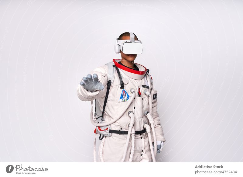 Ethnic astronaut in spacesuit and VR glasses in studio man metaverse cosmos goggles interact explore virtual reality simulate watch male vr gesture portrait