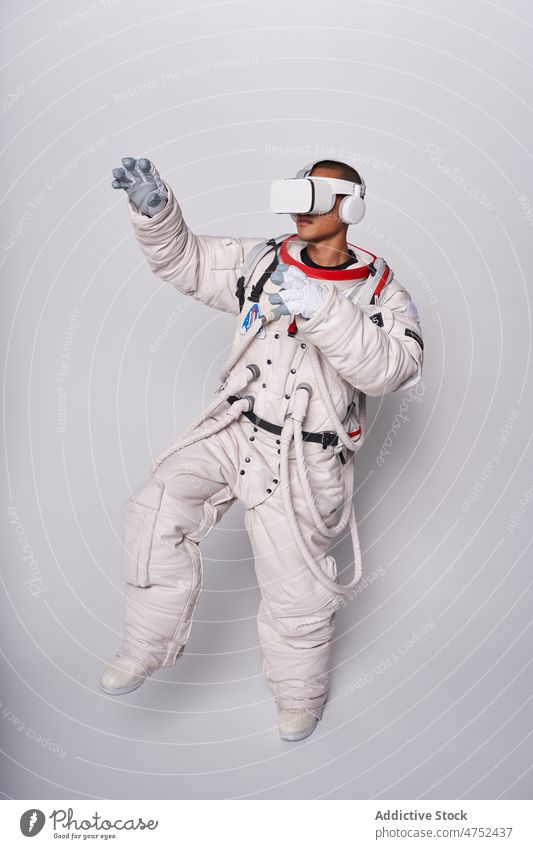 Ethnic astronaut in spacesuit and VR glasses in studio man cosmos goggles interact explore virtual reality metaverse simulate watch male vr gesture technology