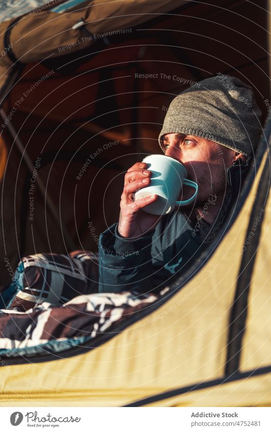 Man drinking hot beverage in camping tent at sunrise man camper morning coffee admire relax recreation freedom male traveler hiker dawn journey blanket campsite