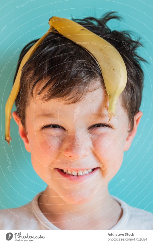 Funny boy with banana peel on head kid having fun childhood carefree playful smile fruit cheerful portrait happy positive fresh sweet glad natural studio