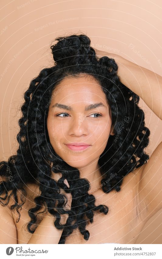 Smiling black woman touching hair touch hair having fun appearance hairstyle feminine ruffle portrait trendy happy studio attractive female charming tousle