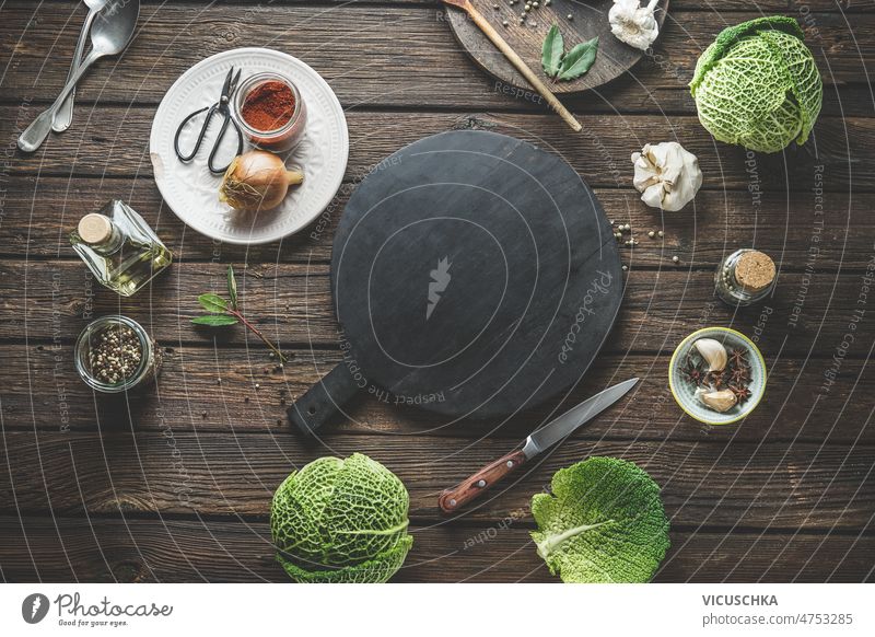 Food background with empty round cutting board, whole savoy cabbage and kitchen utensils food background spices rustic wooden table cooking home healthy