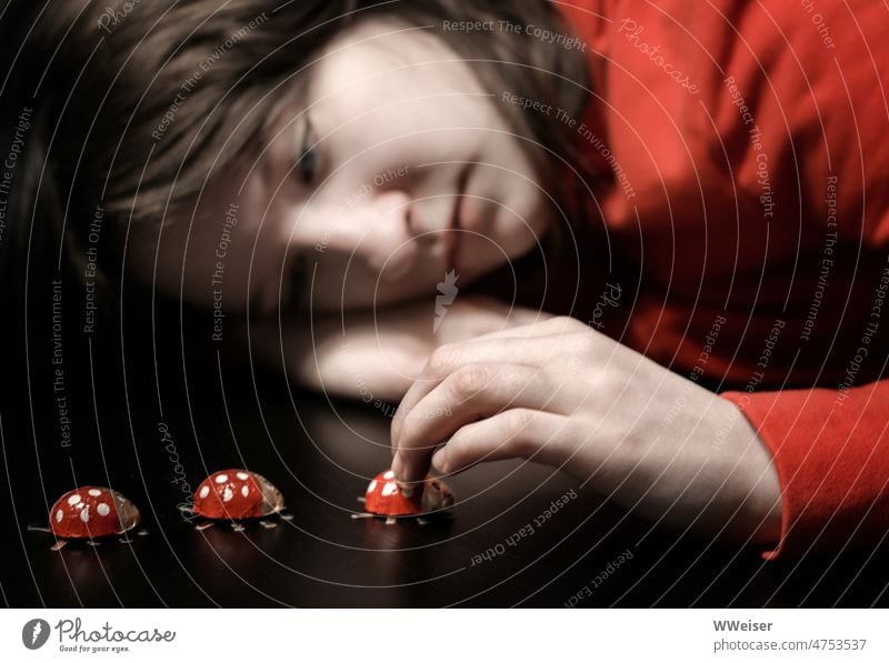 A girl sadly put her head on her arm and dreamily plays with lucky bugs Girl Child Infancy Meditative pensive Dreamily boringly bored Happy lucky beetle