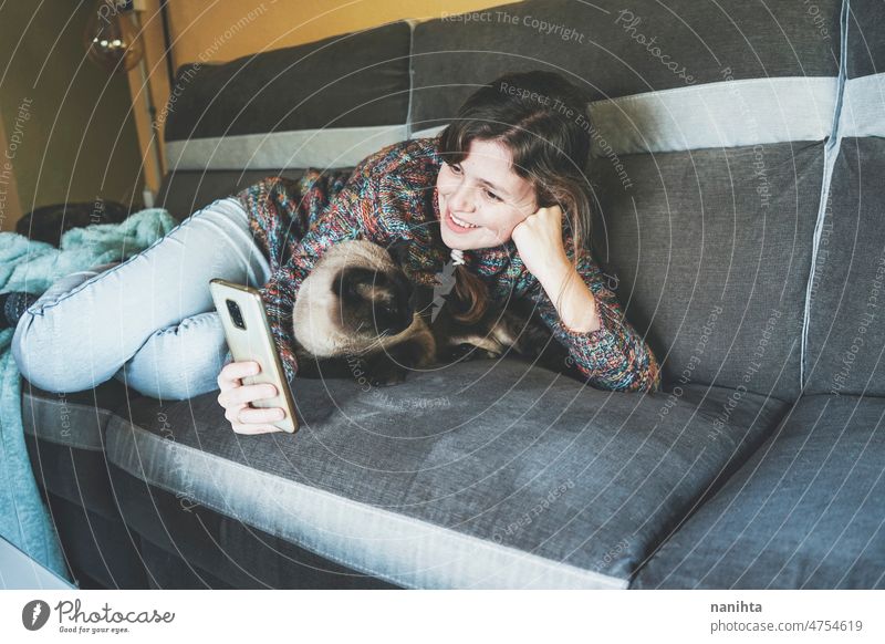 Young woman at home resting with her pet telework single cat social media siamese love family routine technology communication isolate alone lonely happiness