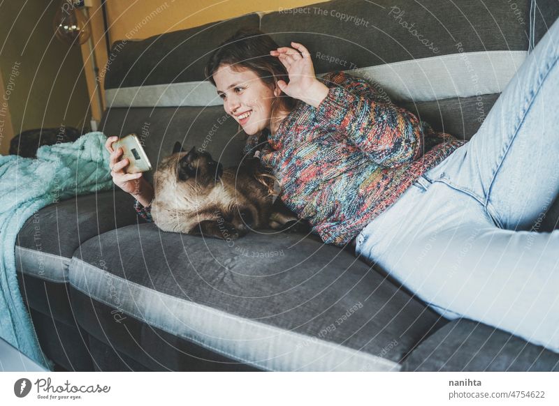 Young woman at home resting with her pet telework single cat social media siamese love family routine technology communication isolate alone lonely happiness