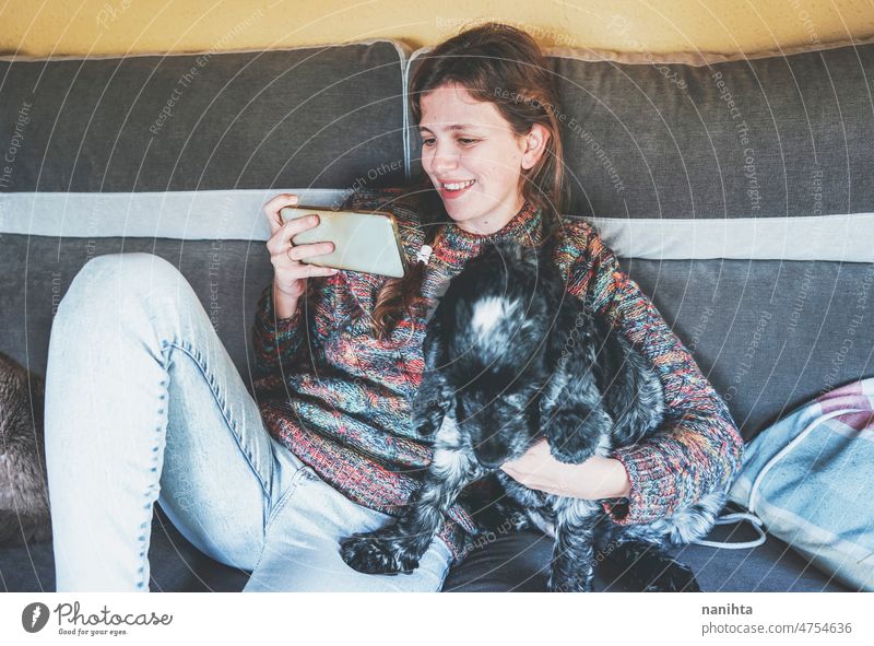 YOung woman using her smart phone white stand with her dog single home family resting sofa mobile happiness happy calm quiet scene care love friends friendship