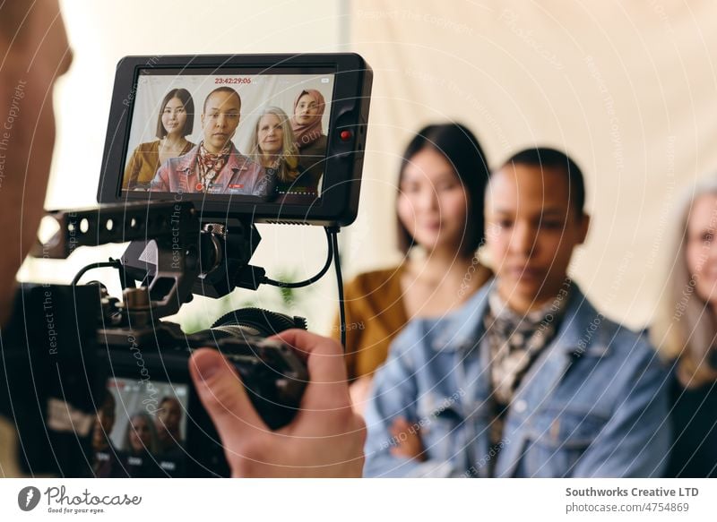 Videographer filming group of multiethnic women for International Women's Day with digital image on camera screen videographer behind the scene BTS on set