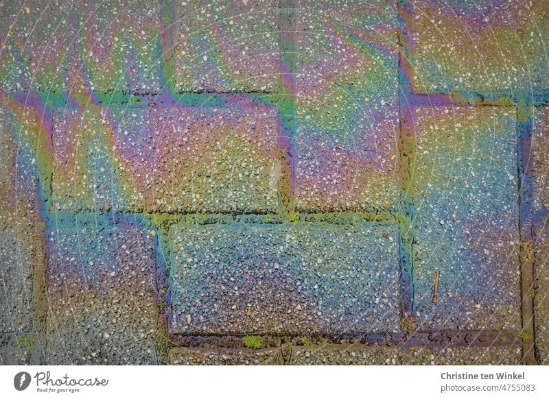 Oil streaks in rainbow colors on paving stones Oil slick Cooking oil Environmental pollution Fuel Patch Fluid Dirty Poison Glimmer Film of oil Oil pollution