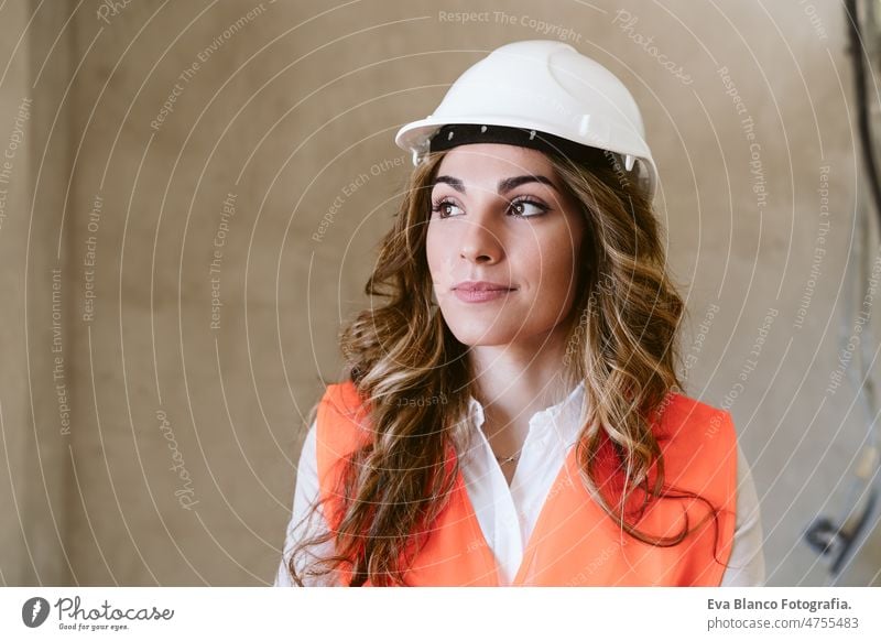 professional confident architect woman in construction site. Home renovation portrait blueprints workspace protective helmet protective jacket mobile phone