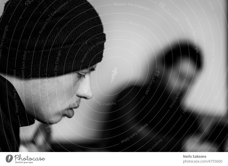 serious young man in black beanie boy guy caucasian human portrait monochrome black and white casual attractive handsome people one silhouette blurred sit