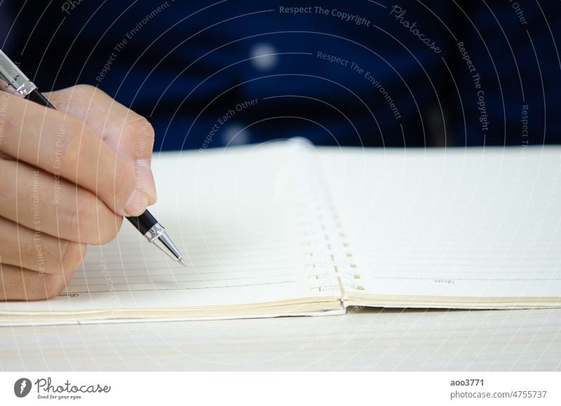 close up holding a pen and writing at the notebook. business paper desk office education diary person document student letter school work white learning study