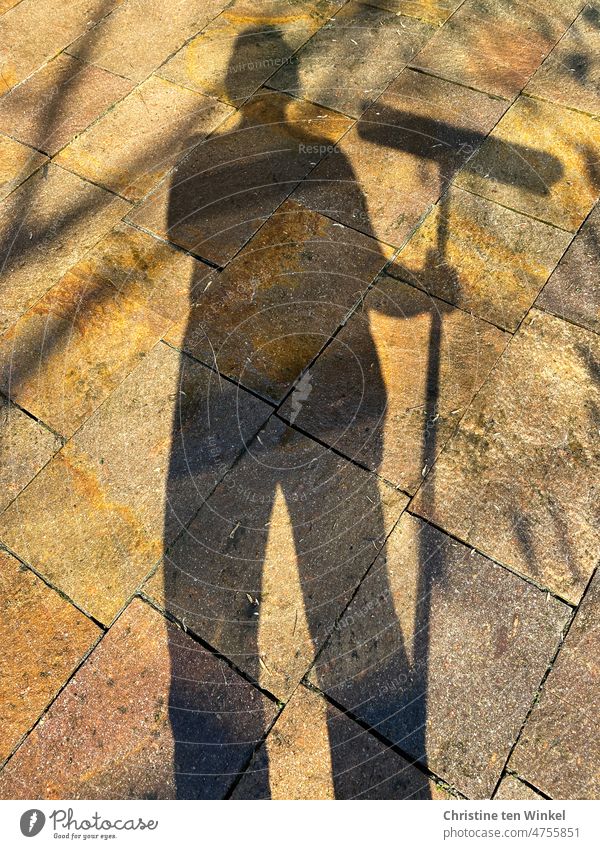 Taking a break from spring cleaning. Shadow man with broom in hand and wet shiny stone slabs on a terrace. shadow woman shadowy Spring cleaning Broom