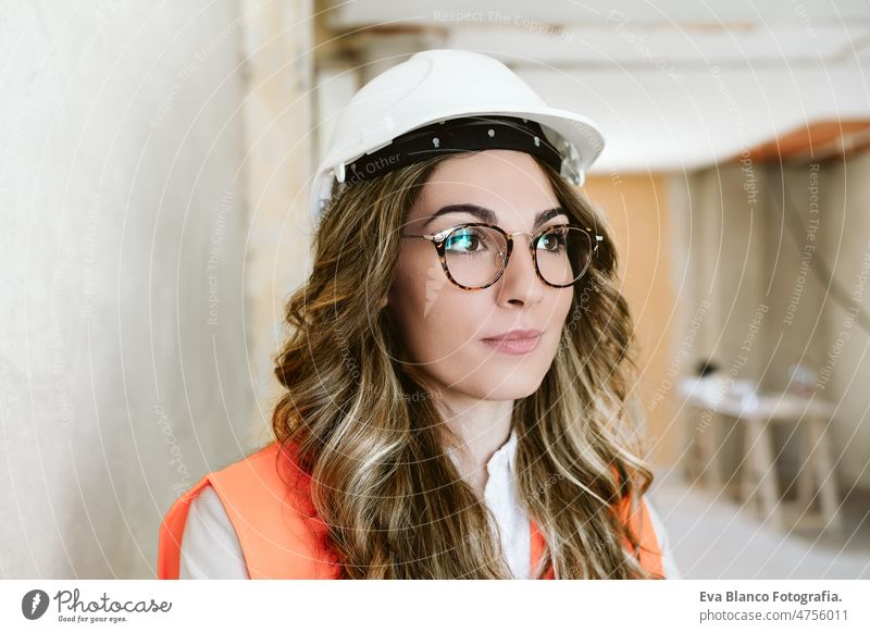 portrait of professional confident architect woman in construction site. Home renovation blueprints workspace protective helmet protective jacket real estate