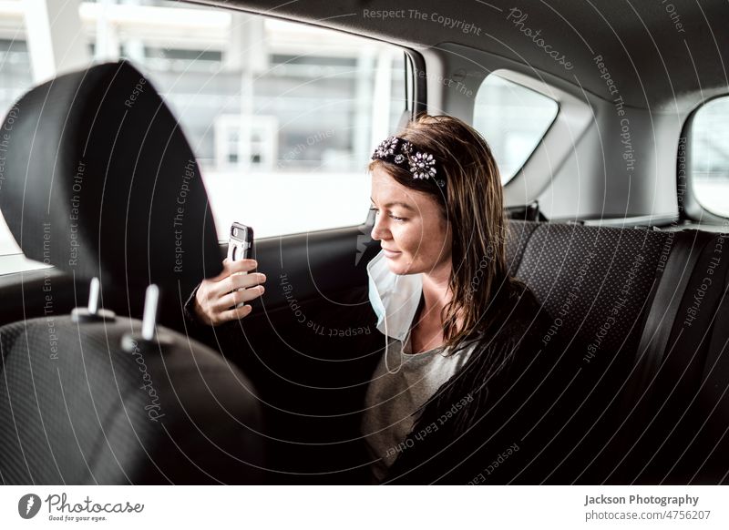 A taxi or Uber passenger talking through the phone on the back seat car woman uber speak showing airport smile person business commuter service customer adult