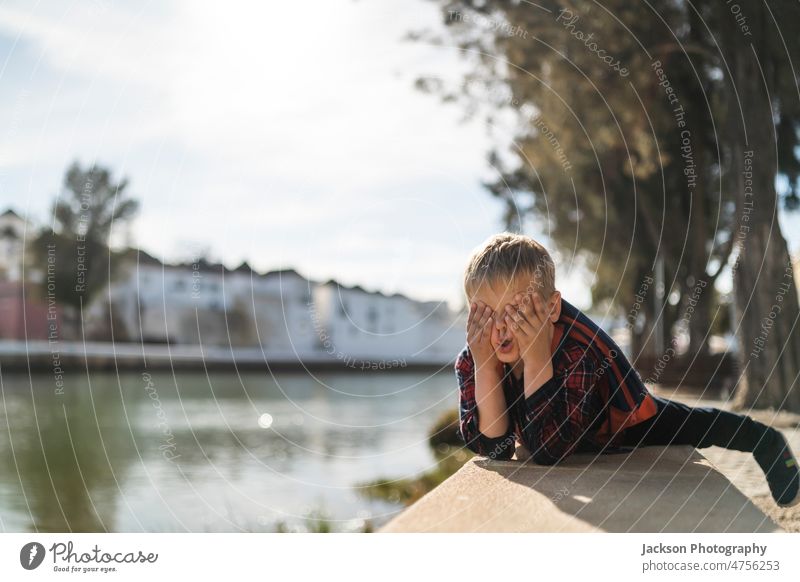 Cute small boy doing faces in his free time by the river kid nature funny do faces play copy space childhood relax backpack vacation outdoors portugal tavira