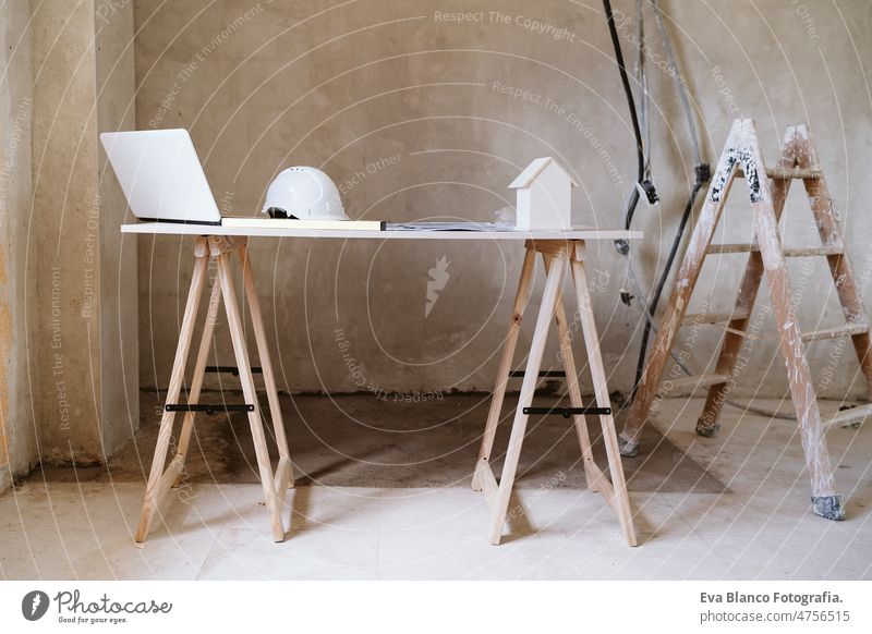 blueprints, protective helmet, laptop,house model and tools on architect workspace.Construction site model house nobody level daytime real state work place home