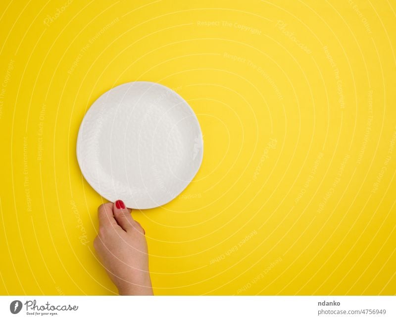 female hand holding a white empty round plate on a yellow background, top view blank bowl ceramic circle clean cooking crockery dining dish dishware flat food