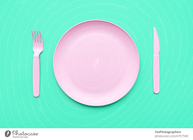 Pink plate and cutlery, above view, on a green table. arrangement background blank breakfast bright ceramics clean close-up color concept cuisine cut out design